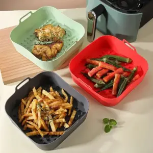 Quadratische Silikonschale mit seitlichen Griffen, daneben ein Airfryer mit Essen