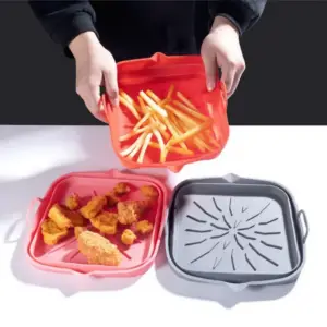 Hände halten eine rote Silikonschale mit Pommes, daneben zwei weitere Schalen mit Nuggets