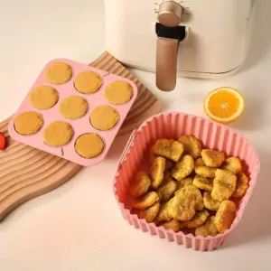 Rosa Silikon-Einsatz mit Nuggets neben einer Muffinform auf einem Holzbrett