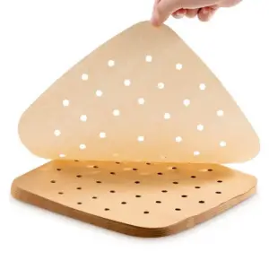 Hand hält eine gelochte braune Backpapier-Einlage über einem Stapel