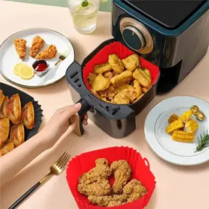 Rote quadratische Einlage mit Nuggets im Airfryer, daneben Geflügel und Mais